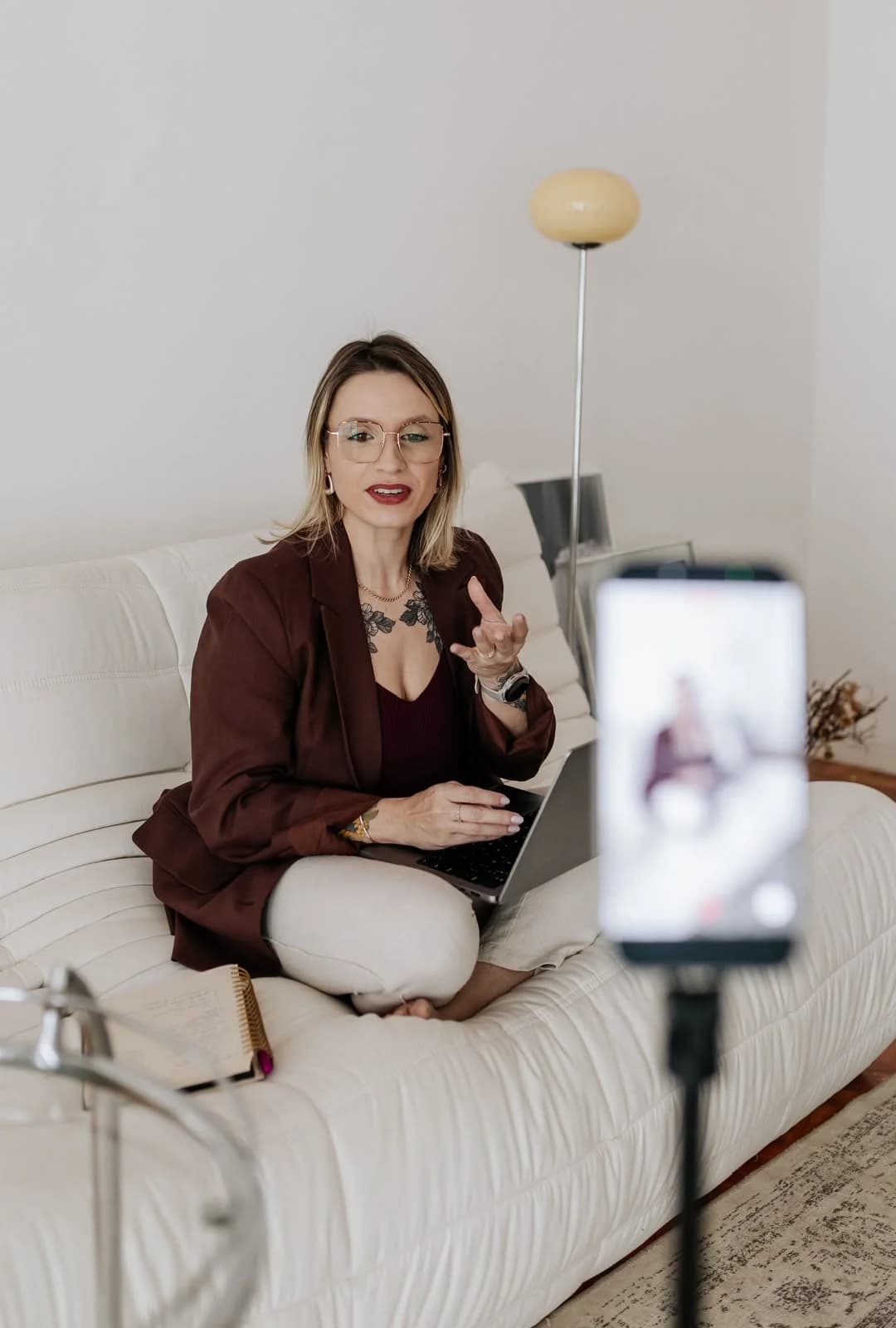 Nathaly Rodrigues conversando diante de um celular em tripé, sentada em um sofá com o notebook
