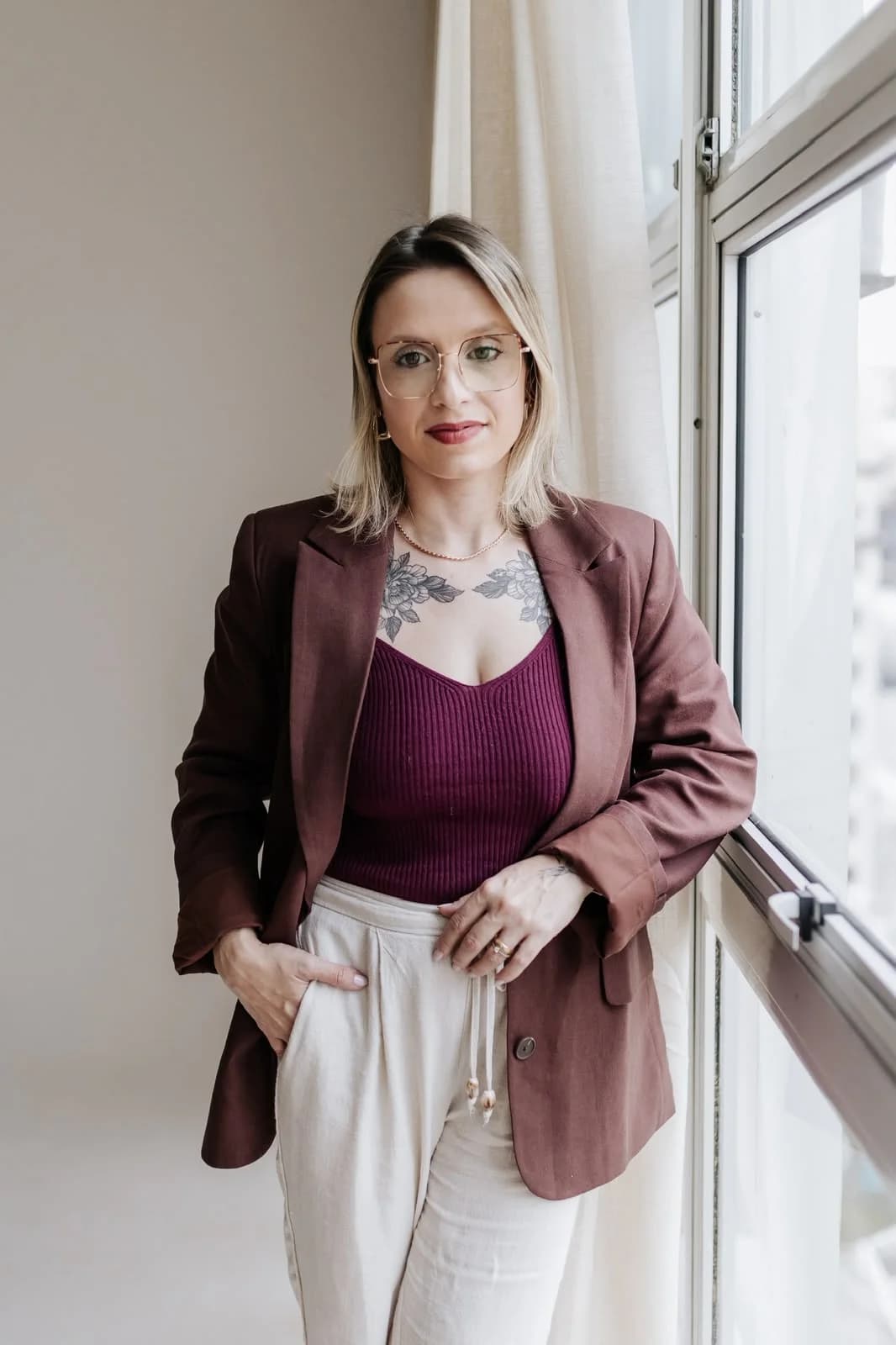 Nathaly Rodrigues, fundadora da DifStart, de blazer bordô, apoiada ao lado de uma janela